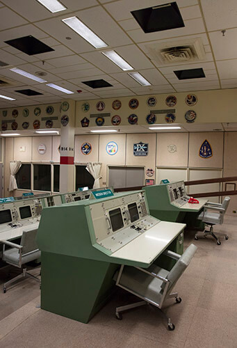 An overall view of the consoles used in Historic Mission Control. The consoles used by multiple flight directors contained no computing elements - they displayed only different information channels coming in from the mainframe. Of the hundreds of buttons, monitors and controls located at these flight controller stations, many have gone missing or have become faded after decades of use.
